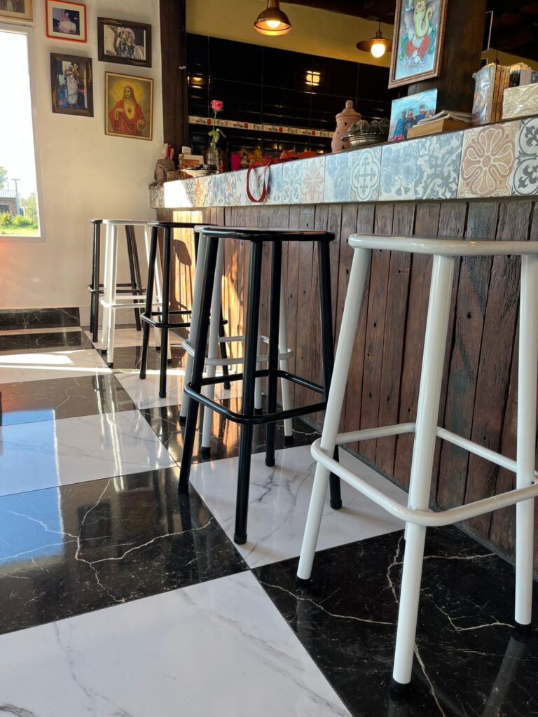 Taburetes blancos y negros frente a la barra en "Experiencia".