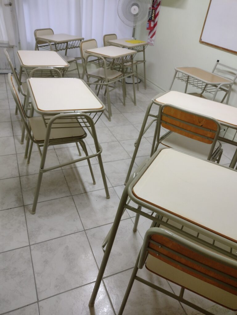 Aula con pupitres vacíos y ventilador. Espacio de "Experiencia" listo para estudiantes.